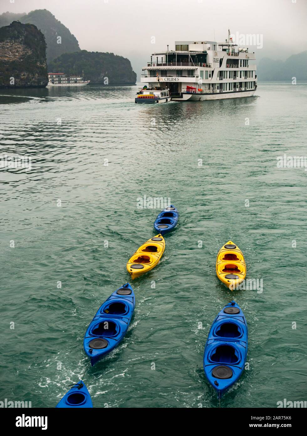 Touristenkreuzfahrtschiff mit Kajaks bei nebeligem Wetter, Lan ha Bay, Vietnam, Asien Stockfoto
