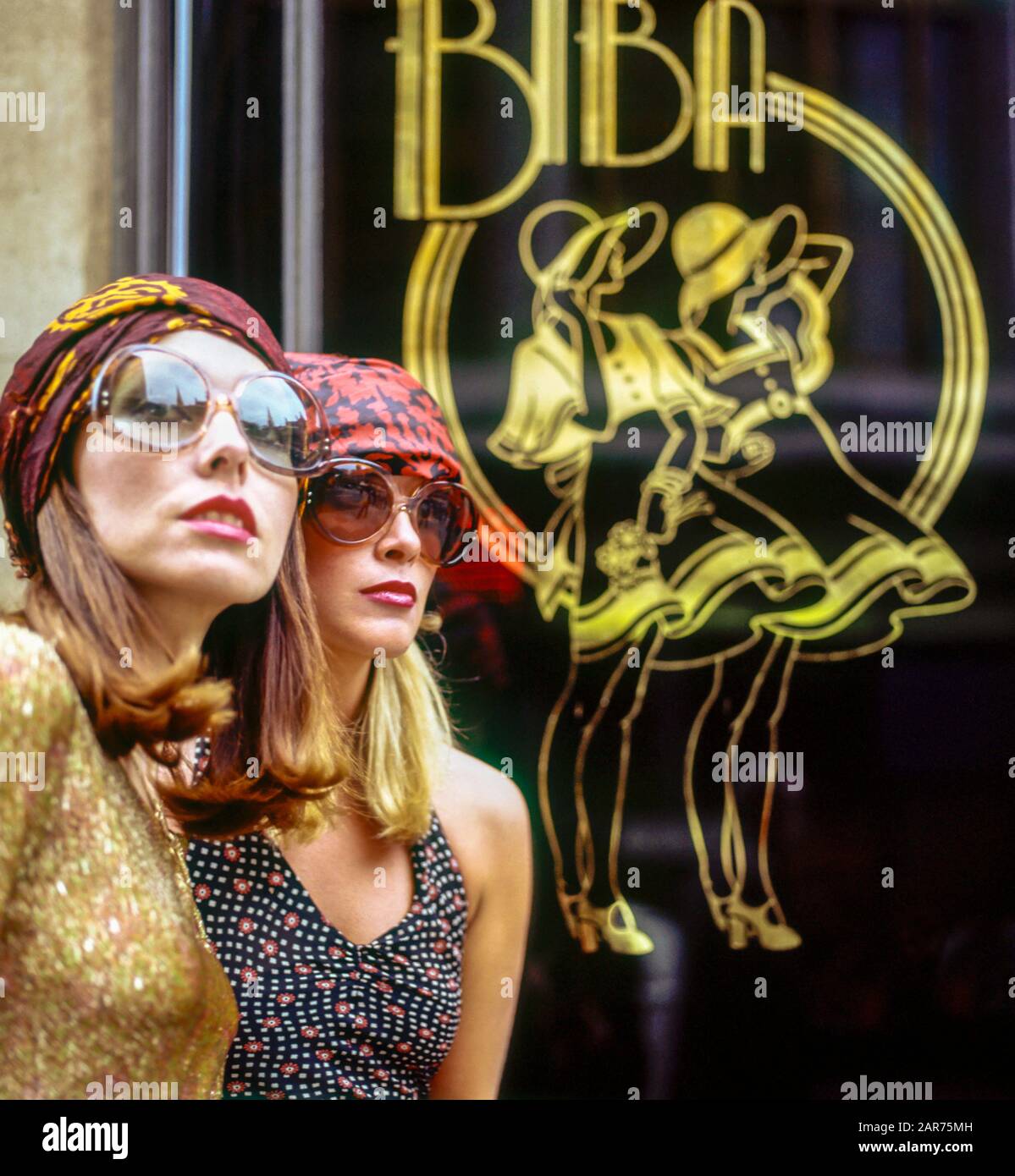 London 1970er Jahre, zwei elegante Frauen Porträt mit Sonnenbrille, Biba Kaufhaus Schild, Kensington High Street, England, Großbritannien, GB, Großbritannien, Stockfoto