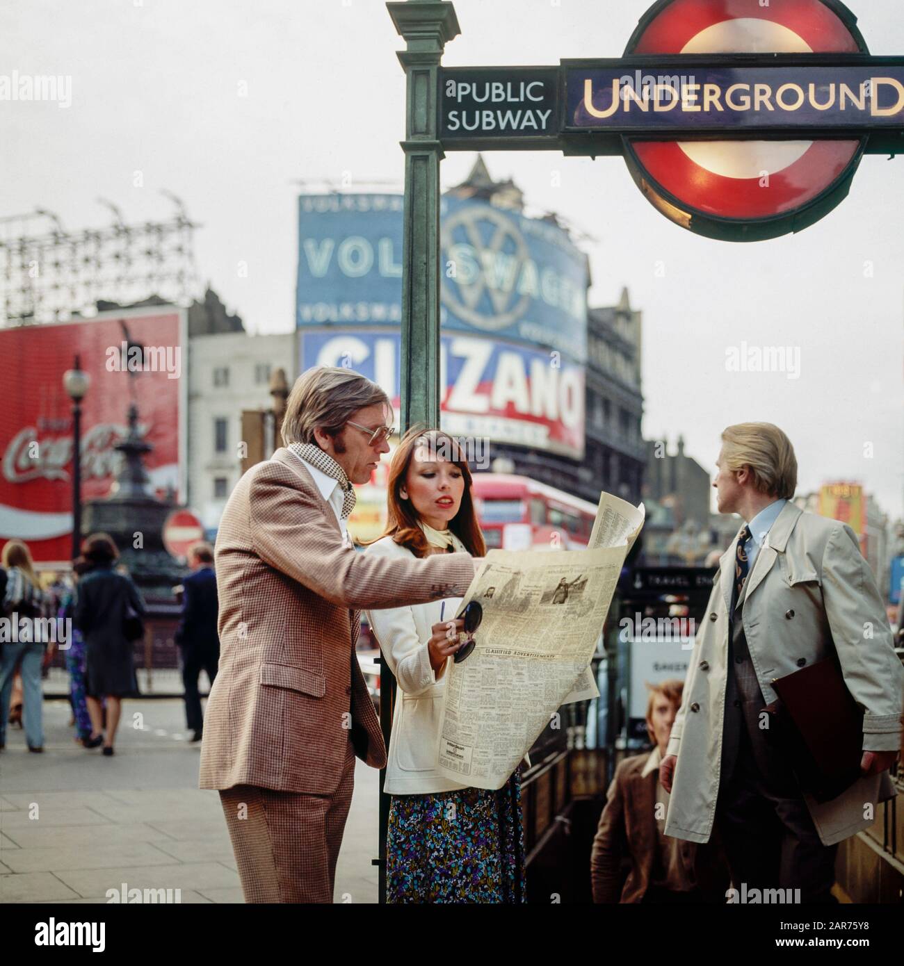 London 1970s, elegante Zeitung für Paare, Ausgang der U-Bahn, U-Bahn-Schild, Abend, Piccadilly Circus, England, GB, GB, Großbritannien, Stockfoto