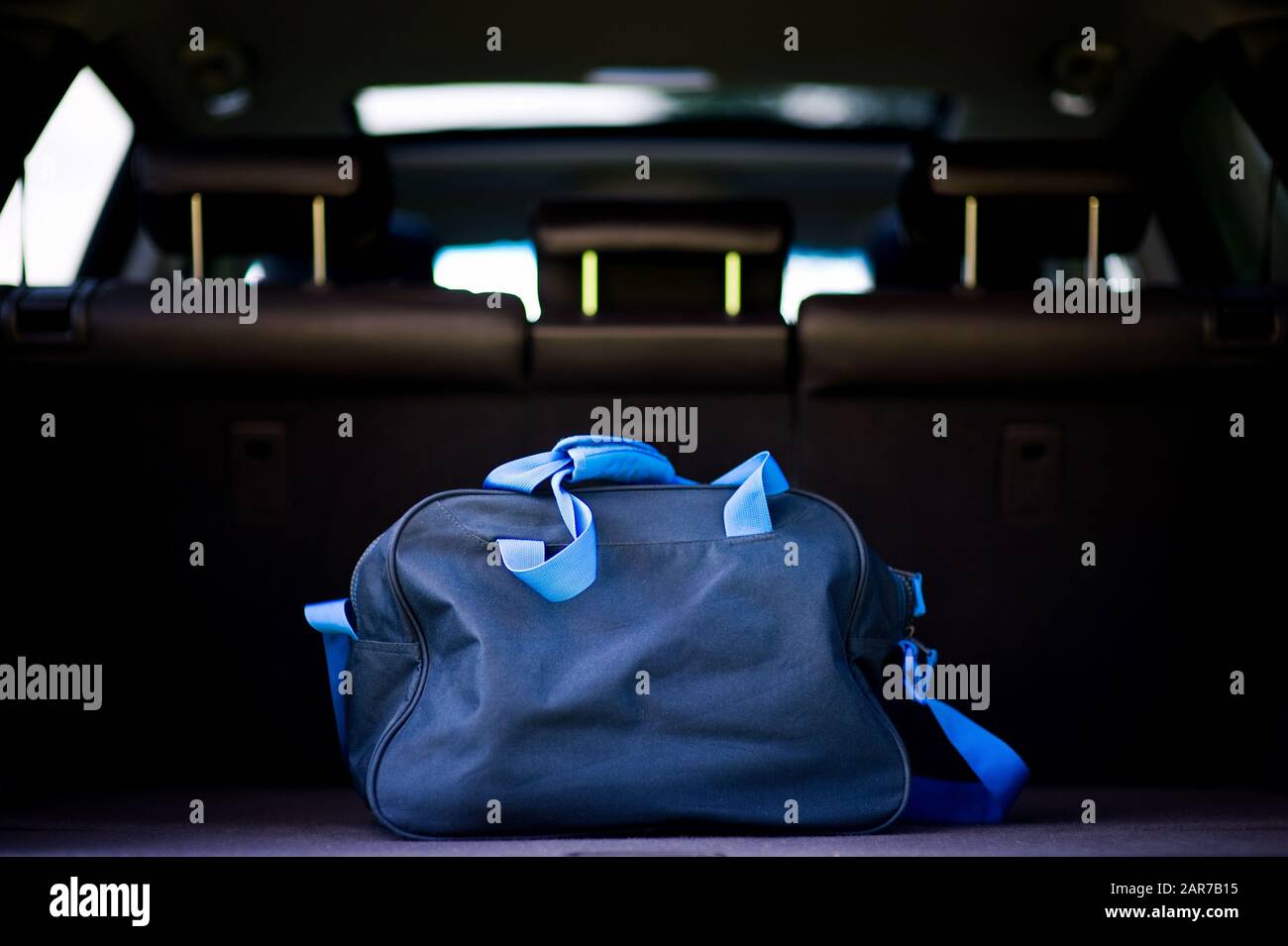 Die blaue Reisetasche des Reisenden liegt im Kofferraum eines SUV Stockfoto