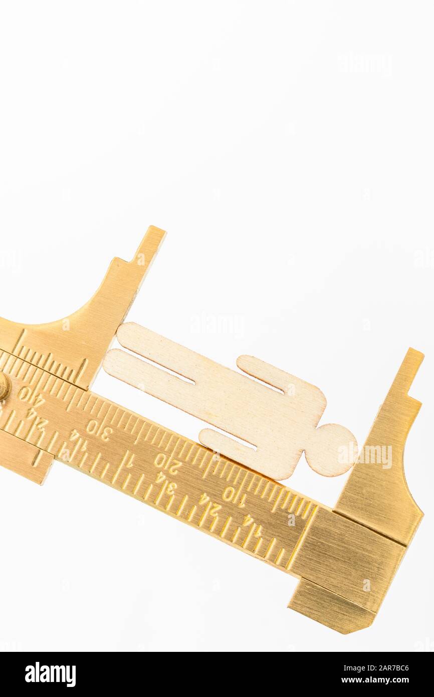 Makro kleine lasergeschnittene Holzfigur und Messing-Zirkel gegen den weißlichen BG. Messung von persönlichen Leistungsindikatoren, demografischen Daten, Produktivität, Stockfoto