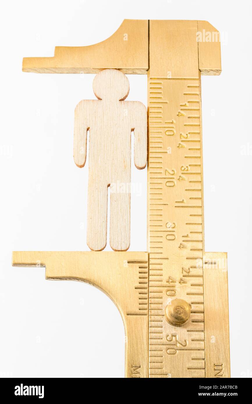 Makro kleine lasergeschnittene Holzfigur und Messing-Zirkel gegen den weißlichen BG. Messung von persönlichen Leistungsindikatoren, demografischen Daten, Produktivität, Stockfoto