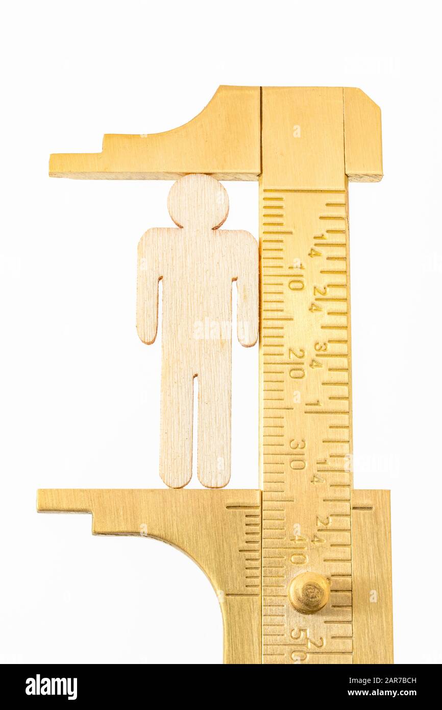 Makro kleine lasergeschnittene Holzfigur und Messing-Zirkel gegen den weißlichen BG. Messung von persönlichen Leistungsindikatoren, demografischen Daten, Produktivität, Stockfoto