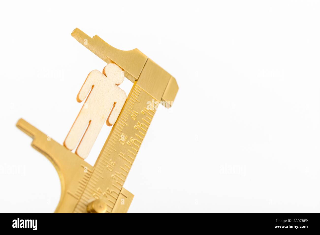 Makro kleine lasergeschnittene Holzfigur und Messing-Zirkel gegen den weißlichen BG. Messung von persönlichen Leistungsindikatoren, demografischen Daten, Produktivität, Stockfoto