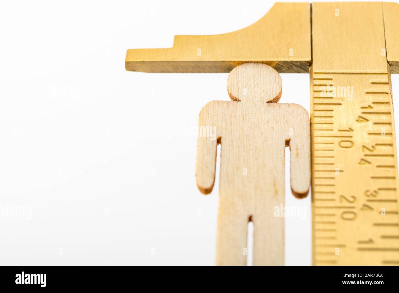 Makro kleine lasergeschnittene Holzfigur und Messing-Zirkel gegen den weißlichen BG. Messung von persönlichen Leistungsindikatoren, demografischen Daten, Produktivität, Stockfoto