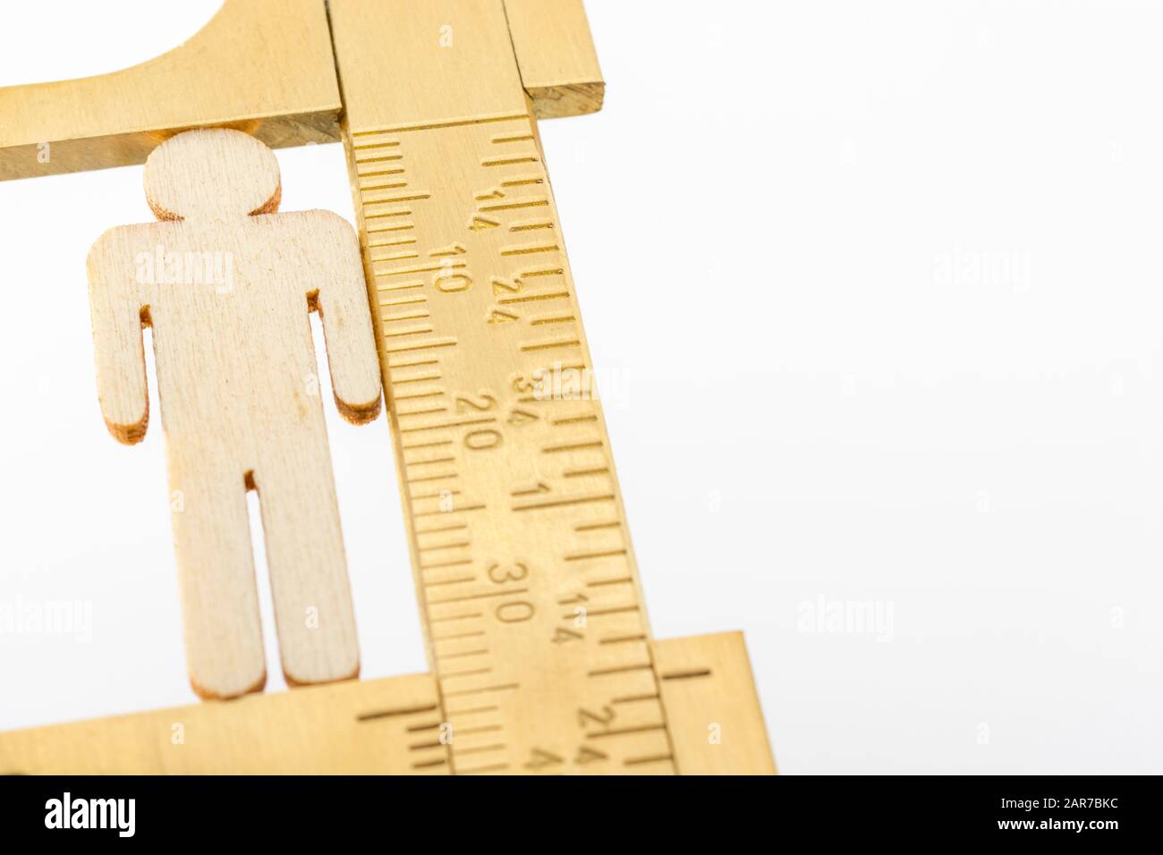 Makro kleine lasergeschnittene Holzfigur und Messing-Zirkel gegen den weißlichen BG. Messung von persönlichen Leistungsindikatoren, demografischen Daten, Produktivität, Stockfoto