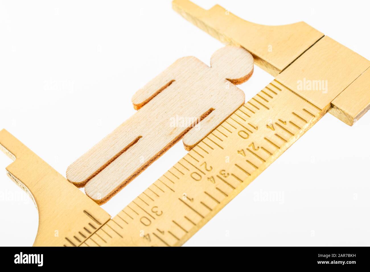 Makro kleine lasergeschnittene Holzfigur und Messing-Zirkel gegen den weißlichen BG. Messung von persönlichen Leistungsindikatoren, demografischen Daten, Produktivität, Stockfoto