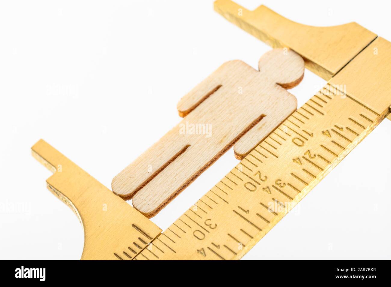 Makro kleine lasergeschnittene Holzfigur und Messing-Zirkel gegen den weißlichen BG. Messung von persönlichen Leistungsindikatoren, demografischen Daten, Produktivität, Stockfoto