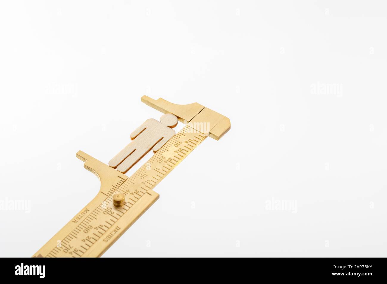 Makro kleine lasergeschnittene Holzfigur und Messing-Zirkel gegen den weißlichen BG. Messung von persönlichen Leistungsindikatoren, demografischen Daten, Produktivität, Stockfoto