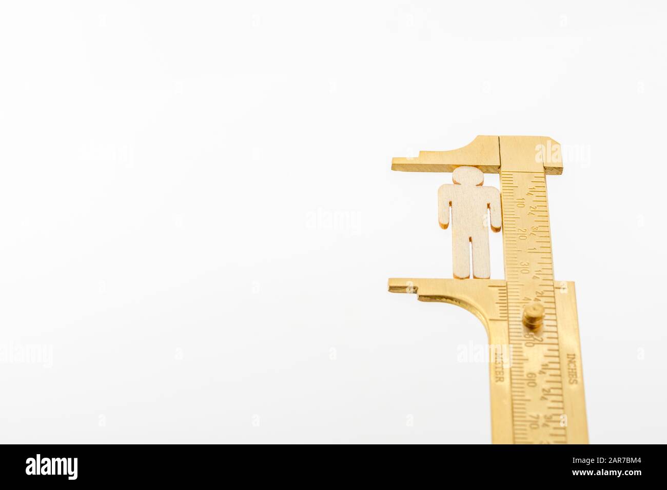 Makro kleine lasergeschnittene Holzfigur und Messing-Zirkel gegen den weißlichen BG. Messung von persönlichen Leistungsindikatoren, demografischen Daten, Produktivität, Stockfoto