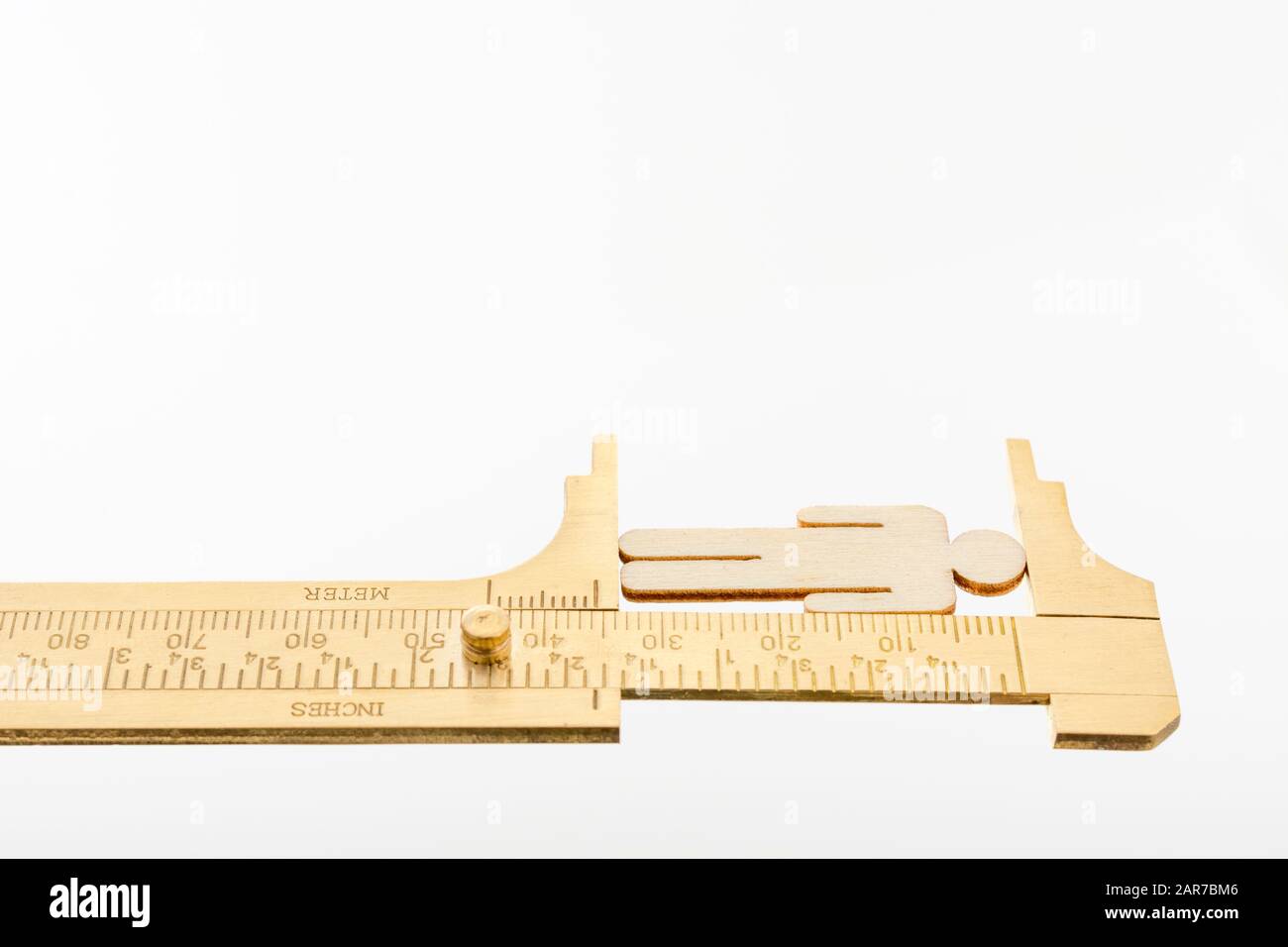 Makro kleine lasergeschnittene Holzfigur und Messing-Zirkel gegen den weißlichen BG. Messung von persönlichen Leistungsindikatoren, demografischen Daten, Produktivität, Stockfoto