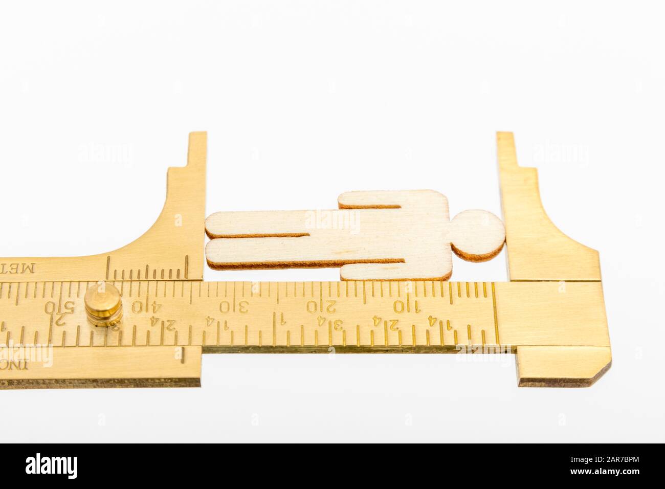 Makro kleine lasergeschnittene Holzfigur und Messing-Zirkel gegen den weißlichen BG. Messung von persönlichen Leistungsindikatoren, demografischen Daten, Produktivität, Stockfoto