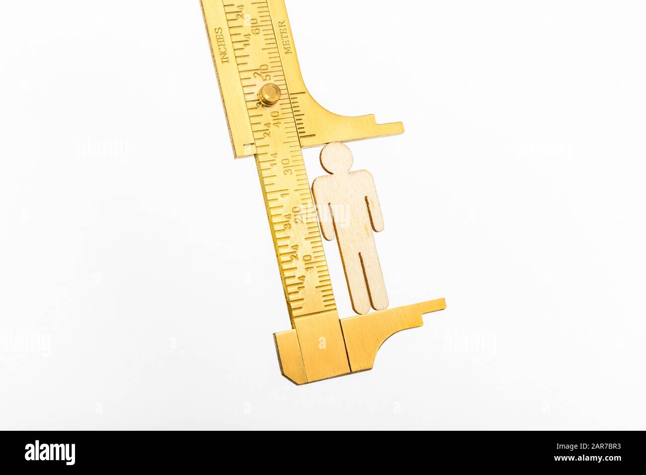 Makro kleine lasergeschnittene Holzfigur und Messing-Zirkel gegen den weißlichen BG. Messung von persönlichen Leistungsindikatoren, demografischen Daten, Produktivität, Stockfoto