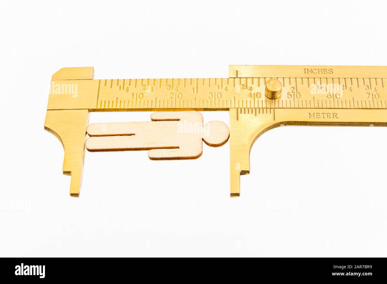 Makro kleine lasergeschnittene Holzfigur und Messing-Zirkel gegen den weißlichen BG. Messung von persönlichen Leistungsindikatoren, demografischen Daten, Produktivität, Stockfoto