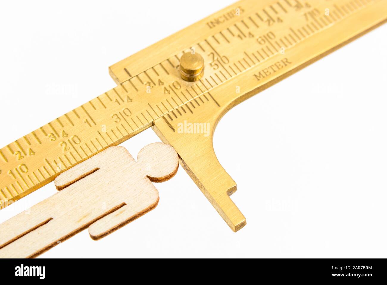 Makro kleine lasergeschnittene Holzfigur und Messing-Zirkel gegen den weißlichen BG. Messung von persönlichen Leistungsindikatoren, demografischen Daten, Produktivität, Stockfoto