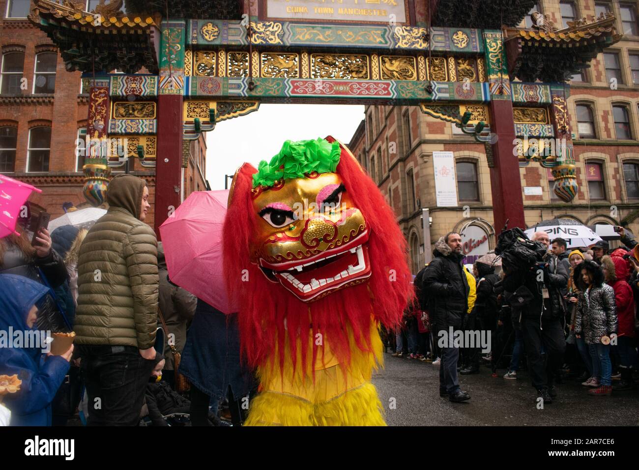 Chinesisches Neujahr Manchester UK mit Löwen, die vor dem chinesischen Bogen in Chinatown tanzen, und Menschenmassen im Hintergrund Stockfoto