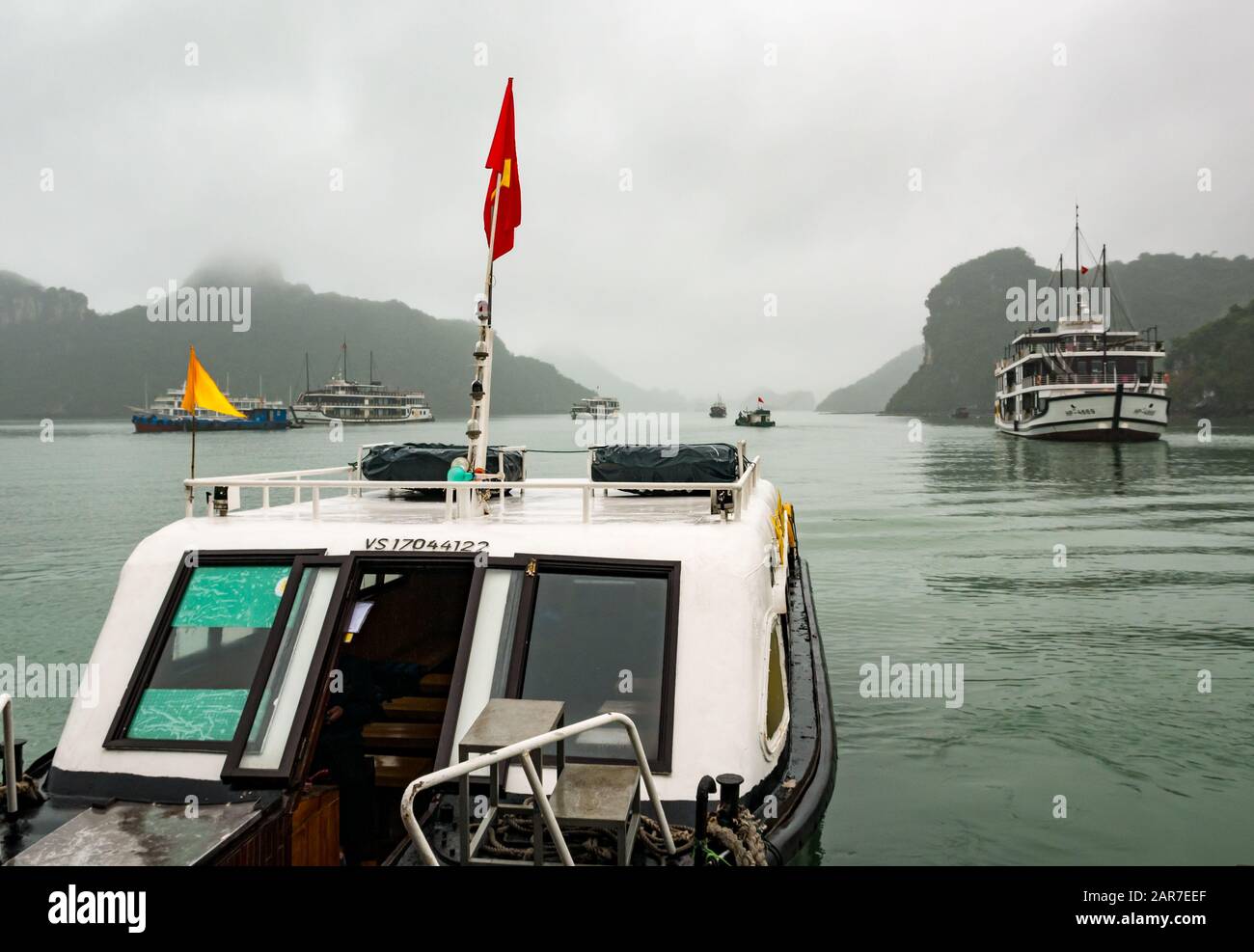 Passagier- und Kreuzfahrtschiffe bei nebligen Wetterbedingungen mit Kalkkarsten, Halong Bay, Vietnam, Asien Stockfoto