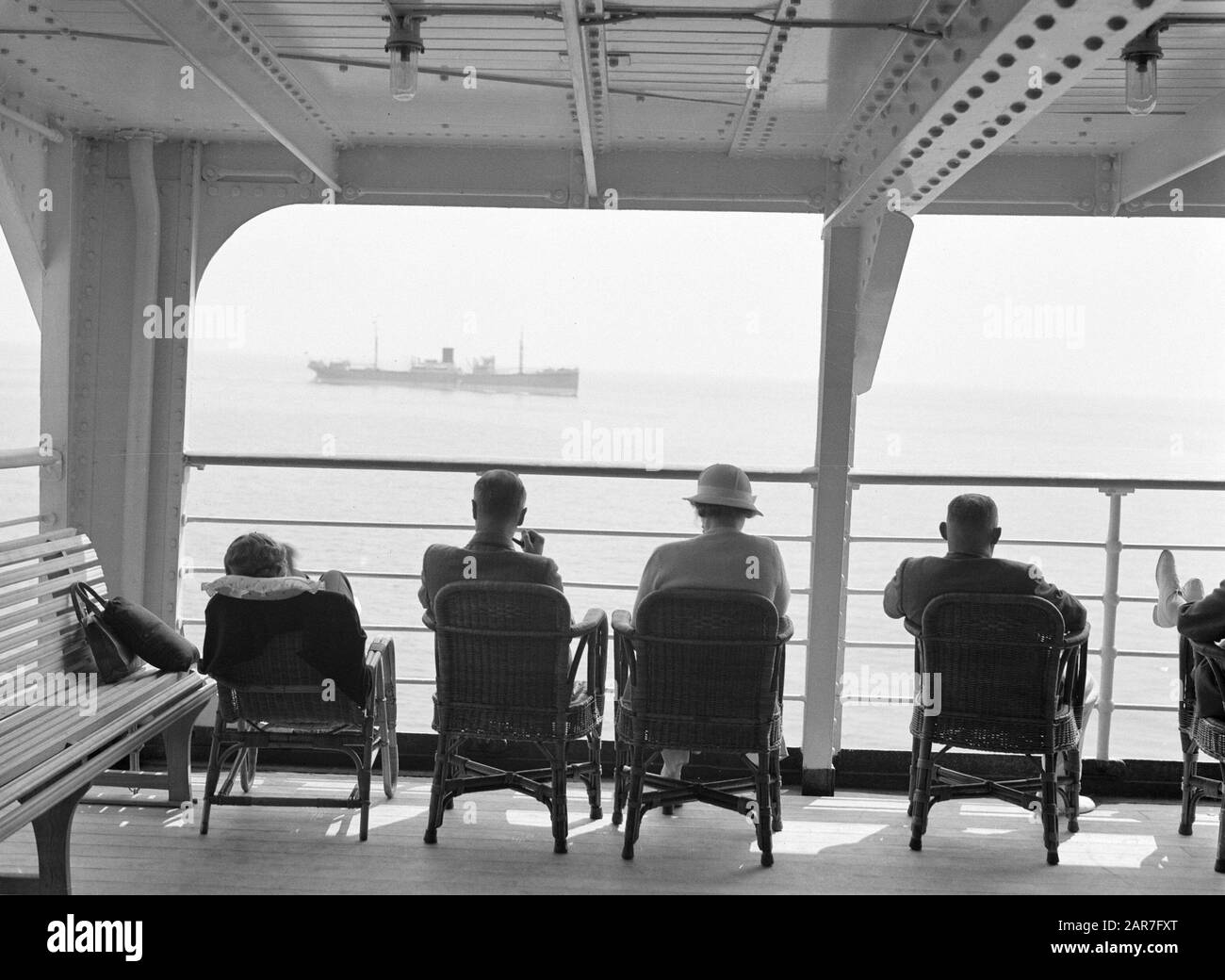 Seereise mit MS Baloeran-Passagieren an Deck; das Frachtschiff ms' Djambi "(1919) von Rotterdamsche Lloyd passiert Anmerkung: Dieses Foto ist Teil einer Reihe von Fotos einer Reise mit der MS Baloeran von de Rotterdam-Lloyd Datum: 1935 Schlüsselwörter: Passagierschiffe, Reisende Stockfoto
