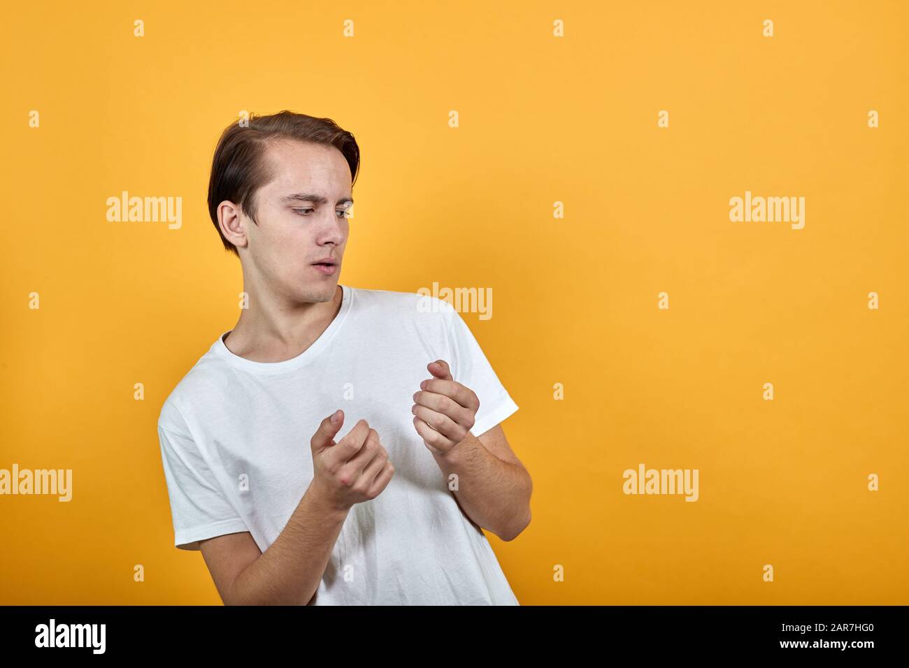 Ein junger Mann in weißem T-Shirt hält seine Hände, in die man etwas einstecken kann. Stockfoto