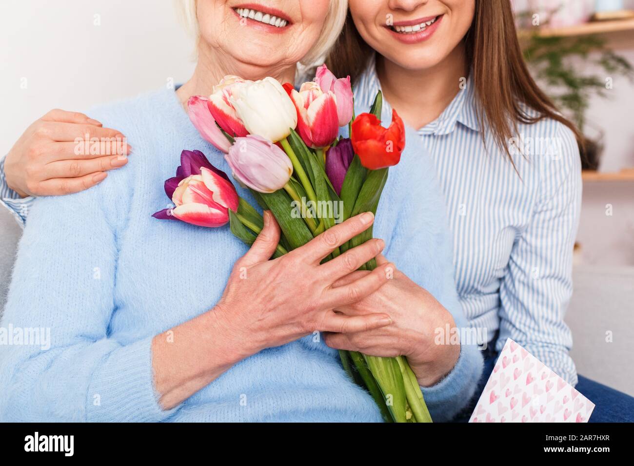 Alte Frau mit Tochter umarmen und halten Blumen Stockfoto