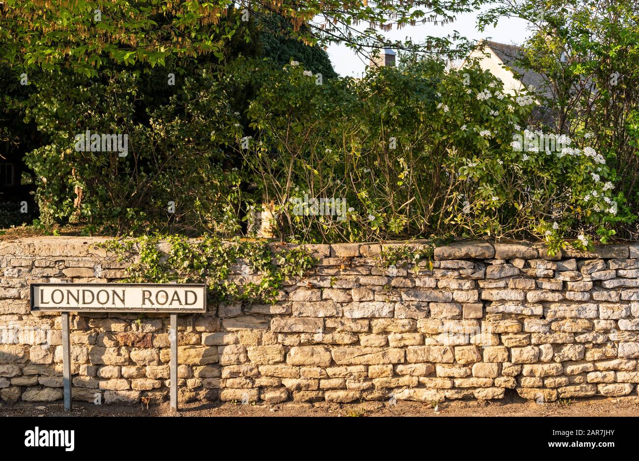 Ein Straßenschild mit der Aufschrift London Road und eine Steinmauer aus lokalem Jurassic Kalkstein in Wansford, Cambridgeshire, England gebaut Stockfoto