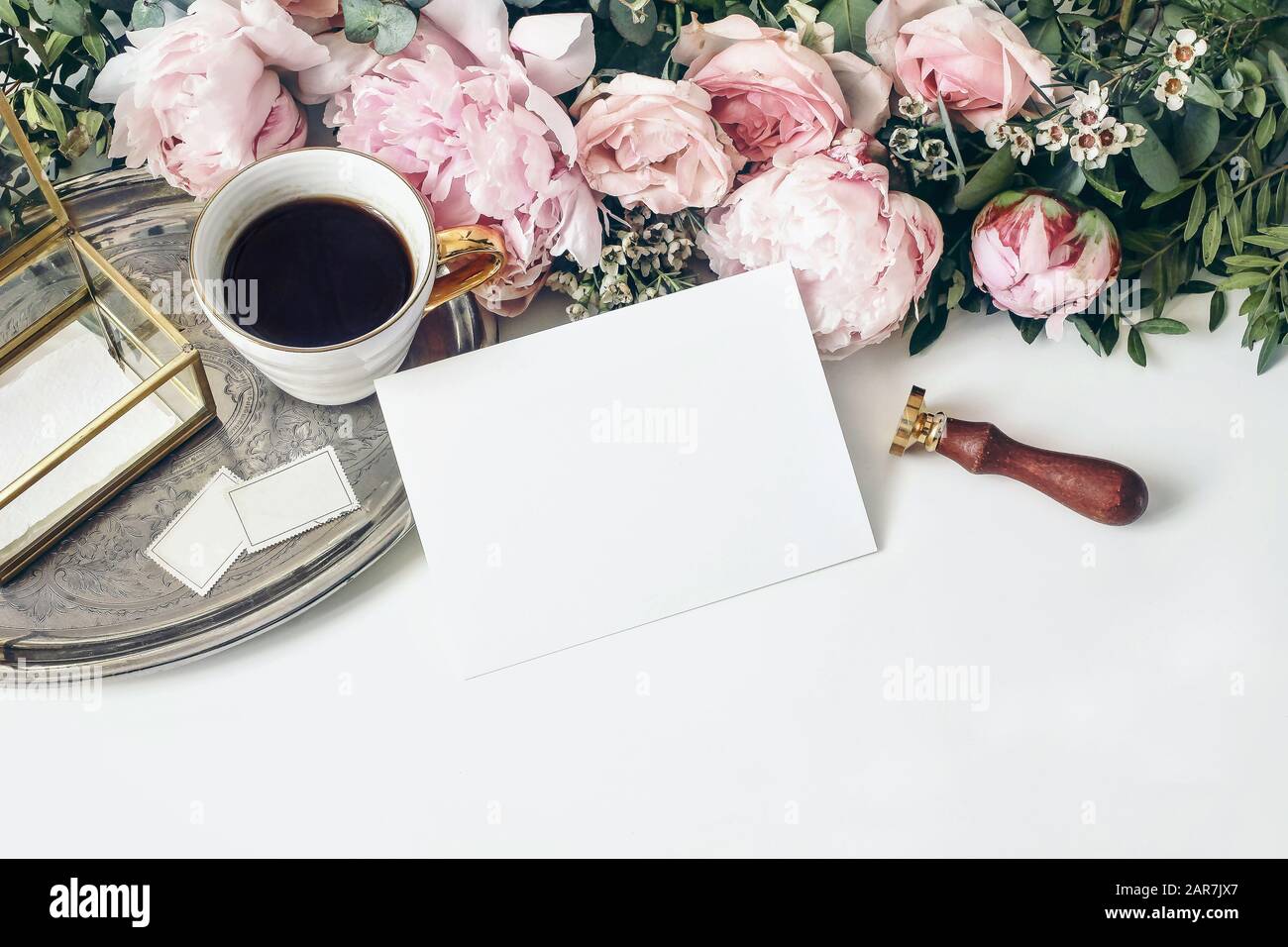 Feminine Hochzeit, Geburtstagskomposition. Rosa Ponys, Rosen-Blumen, Eukalyptus, Kaffeetasse auf silbernem Tablett Goldener Kasten und Siegelstempel auf weißem Tisch B. Stockfoto