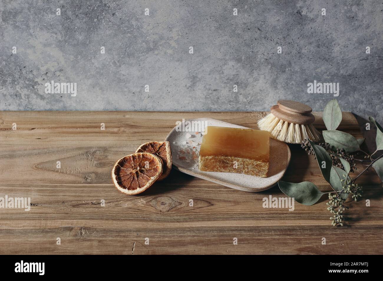 Stillleben von organisch handgefertigter Seifenleiste, Holzbürste und trockenen Zitronen ruit und Eukalyptus auf Holztisch. Spa, Konzept für pflanzliche Kosmetik. Grunge defocu Stockfoto