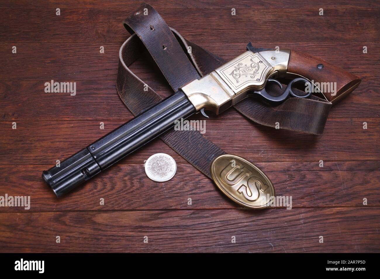Wild West Weapon - Vulkanische Repetierpistole mit Gürtel der US Army mit Schnalle und Silber-Dollar auf Holztisch Stockfoto
