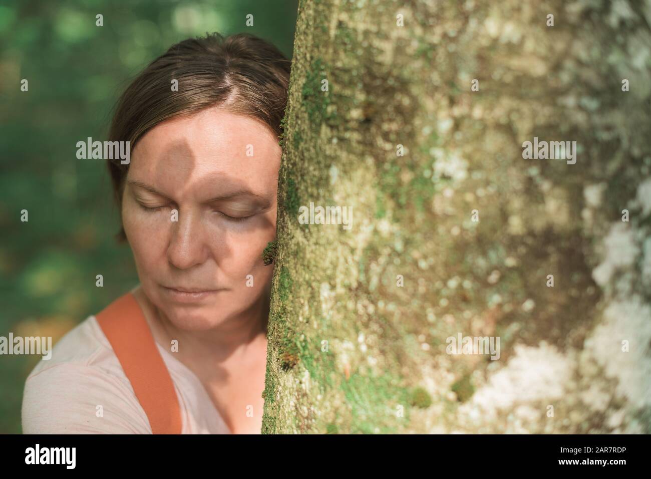 Frau umarmt Baumstamm im Wald, weibliche Umweltschützerin mit ihren Armen um den Baum, selektiver Fokus Stockfoto