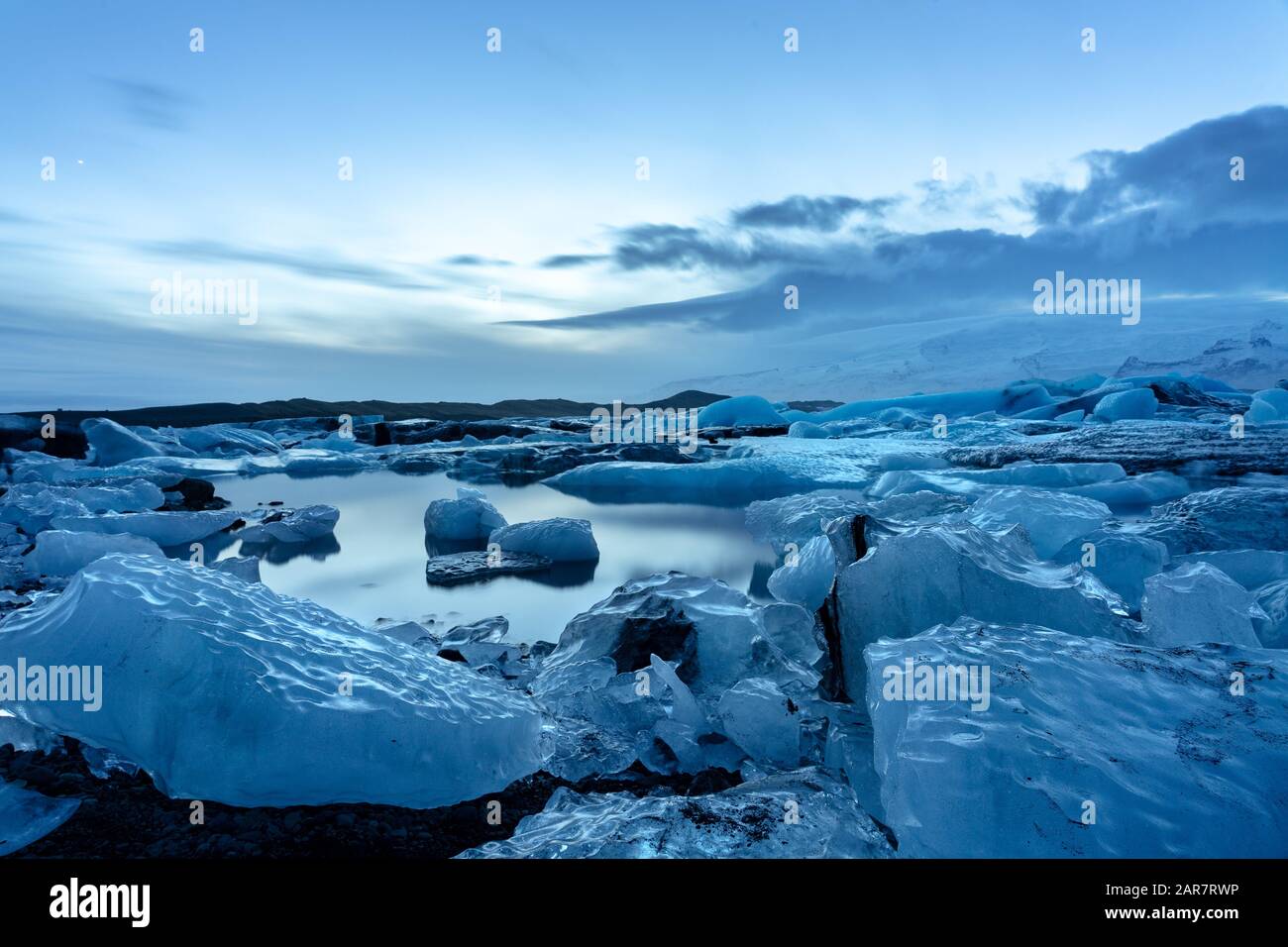 Island-Gletscher jokulsarlon am Abend Eisberge, die auf dem kalten, friedlichen Wasser nach Sonnenuntergang mit dramatischem Himmel schweben. Stockfoto
