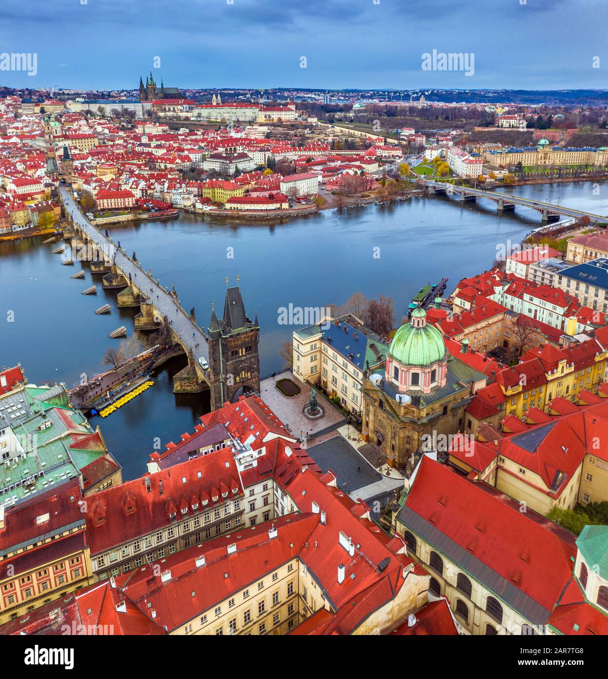 Prag, Tschechien - Panorama-Dronenblick auf die weltberühmte Karlsbrücke (Karluv Most) und die St.-Franz-Assisi-Kirche auf einer Winterpost Stockfoto
