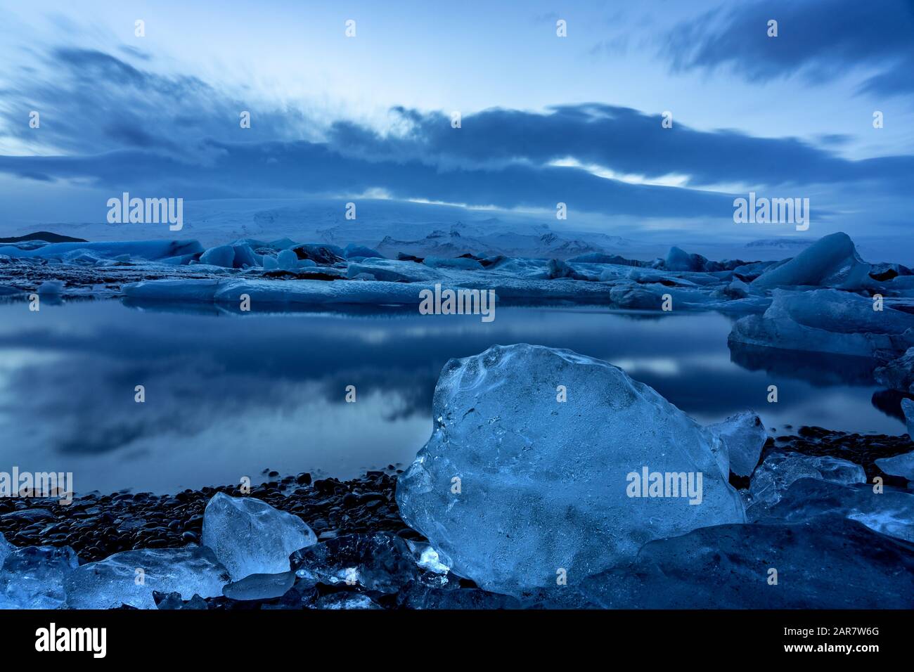 Island-Gletscher jokulsarlon am Abend Eisberge, die auf dem kalten, friedlichen Wasser nach Sonnenuntergang mit dramatischem Himmel schweben. Stockfoto