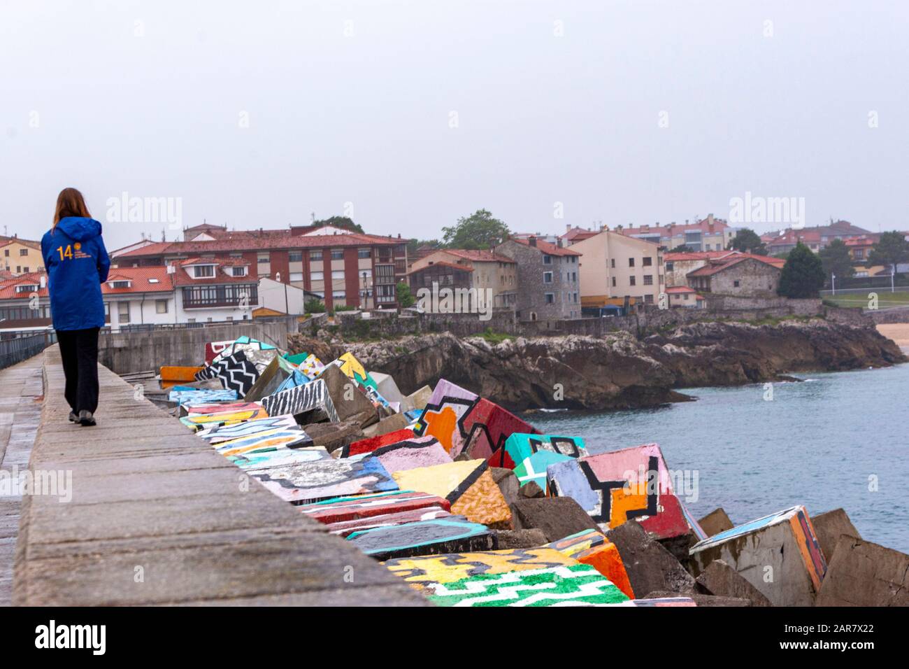 Frau, die mit Los Cubos de la Memoria, Den Memoria Cubes, durch Agustín Ibarrola im Hafen von Llanes, Asturien, Spanien, spaziert Stockfoto
