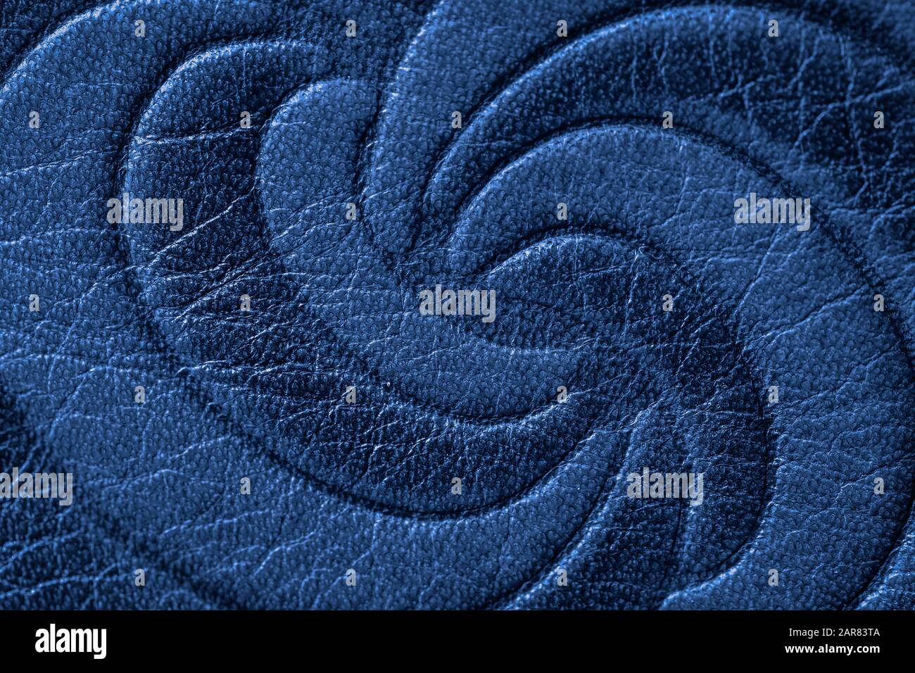 Struktur aus dunkelblauem echtem Leder Nahaufnahme, mit eingeprägter Spiralkurve, Spirale und Trendmuster. Modischer Hintergrund für Bannerdesign Stockfoto