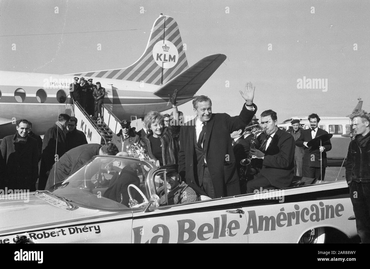 Robert Dhery, der französische Regisseur des Films La Belle Americaine mit Frau und Schauspielerin Colette Brosset am Flughafen Schiphol (+ das ursprüngliche Auto der Belle Americaine, auf dem der Text der My Fair Lady aufgebrochen ist] Datum: 22. Februar 1962 Ort: Schiphol, Zuid-Holland Schlüsselwörter: Schauspielerinnen, Autos, Film, Filmregisseure, Filmstars, Flughäfen persönlicher Name: Brosset, Colette, Dhery Robert Stockfoto