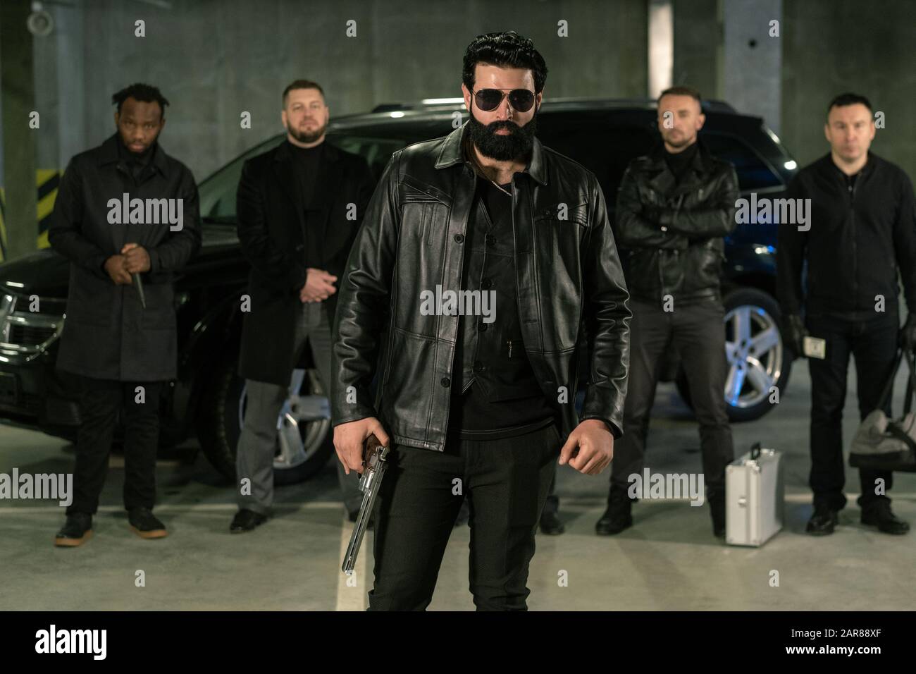 Bärtige Strafvollmacht in Sonnenbrille, schwarzer Lederjacke und Jeans Stockfoto