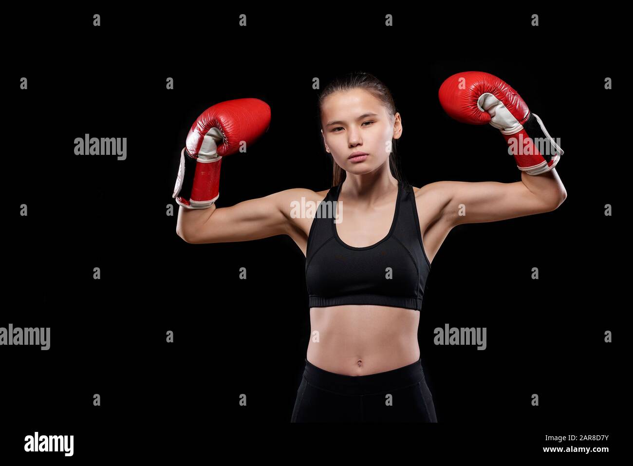 Junge starke Mixed-Race-Sportlerin mit Aktiv-Ohr- und Boxhandschuhen Stockfoto