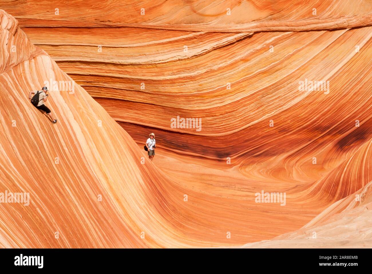 Zwei Menschen erkunden die markanten geologischen Felsformationen auf der WELLE im Norden Coyote Butte, Page, Arizona Stockfoto