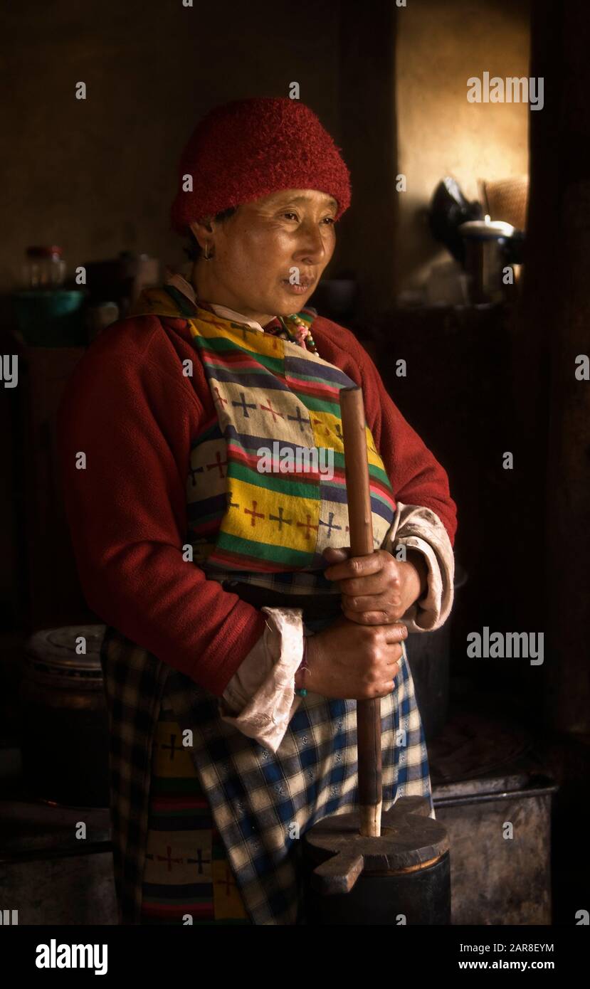 Bhutanerin schürft Yakbutter in ihrem Bauernhaus Ura Valley, Bhutan, Asien Stockfoto