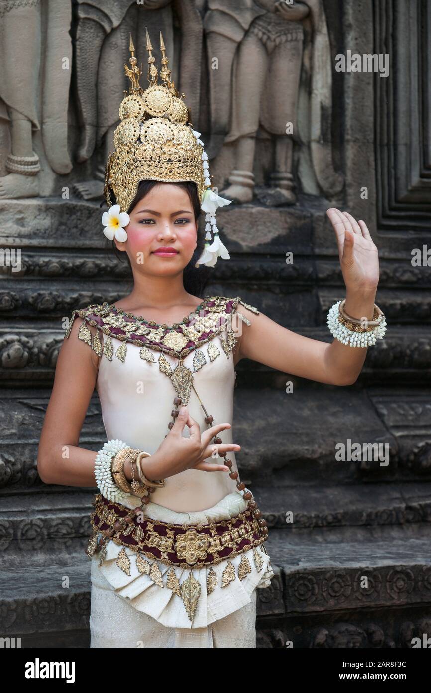 Schöne traditionelle Apsara-Tänzerin posiert in einem cremefarbenen Kleid, kunstvolle Goldmaske vor den Ruinen von Angkor Wat, Siem Reap, Kambodscha Stockfoto