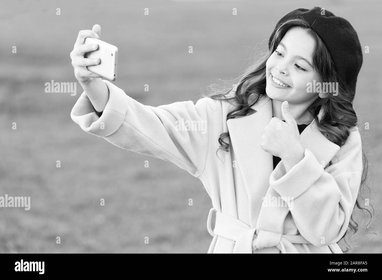 Netten Schuß. Anwendung für Smartphone. Moderne Kommunikation. Mädchen halten Smartphone unter selfie. Selfie für soziale Netzwerke. Streaming online oder Schießen Vlog. Kind, Mädchen, Lächeln, Halten Smartphones. Stockfoto