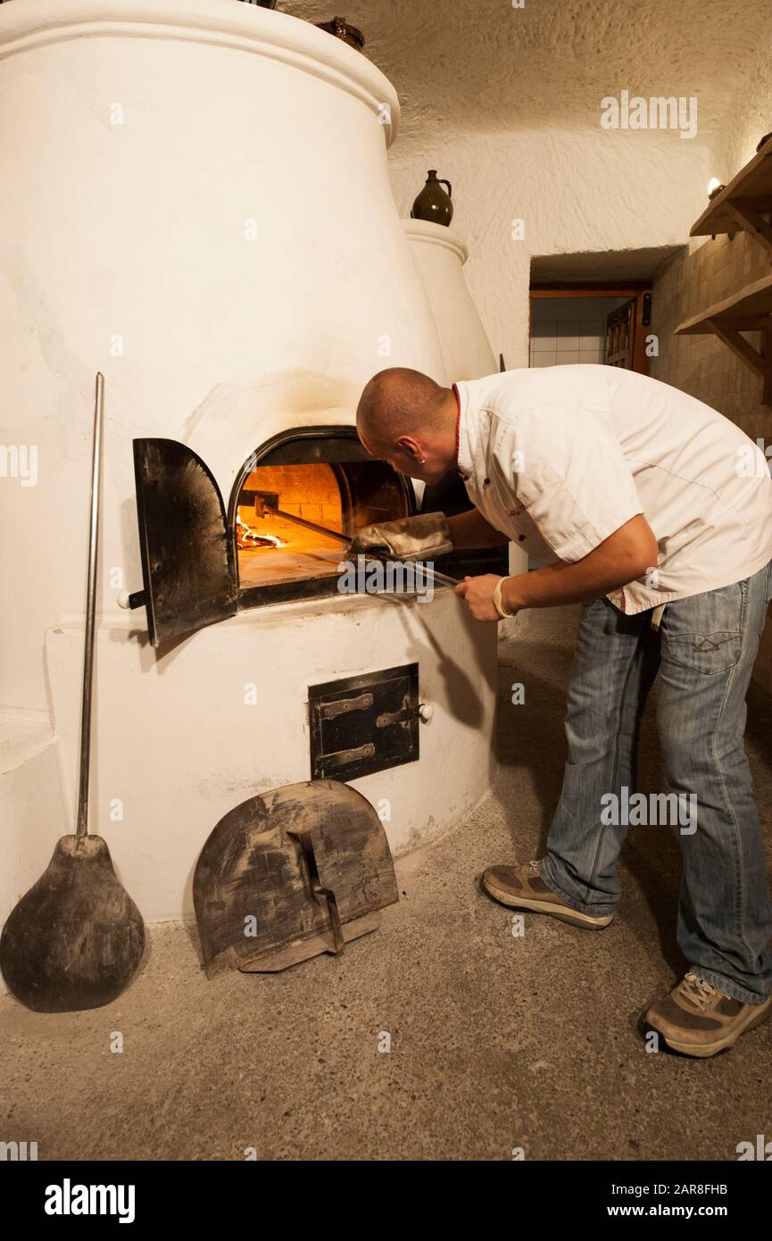 Mann, der in der Küche in Thummerer Weingut, Noszvaj Dorf, Eger, Ungarn, Osteuropa Feuer in Ton rüber pochte Stockfoto