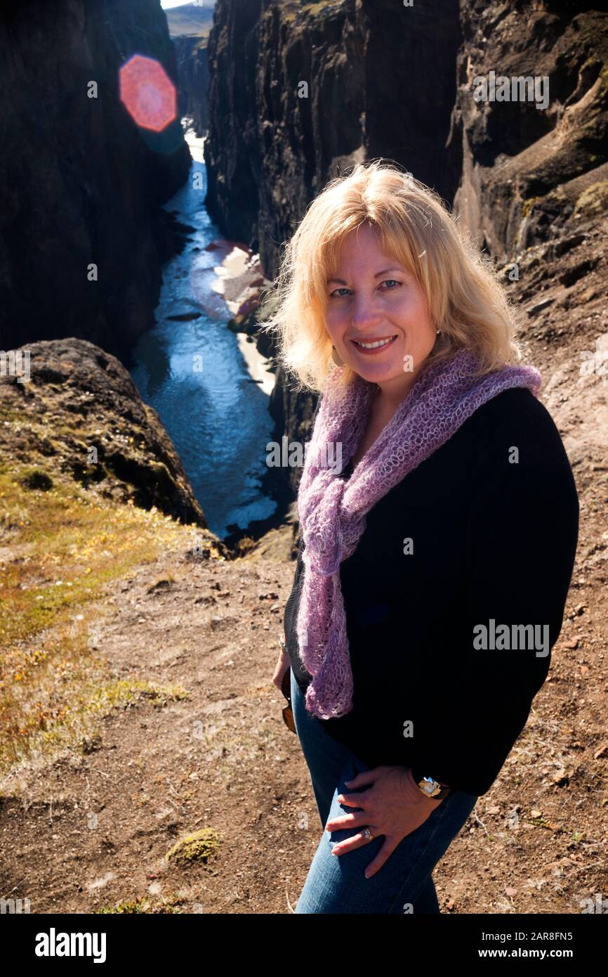 Weiblicher Tourist steht über einem Fluss, der durch einen schmalen Canyon im Norden Islands verläuft, Hafrahvammaglijufrum, Island, Europa Stockfoto