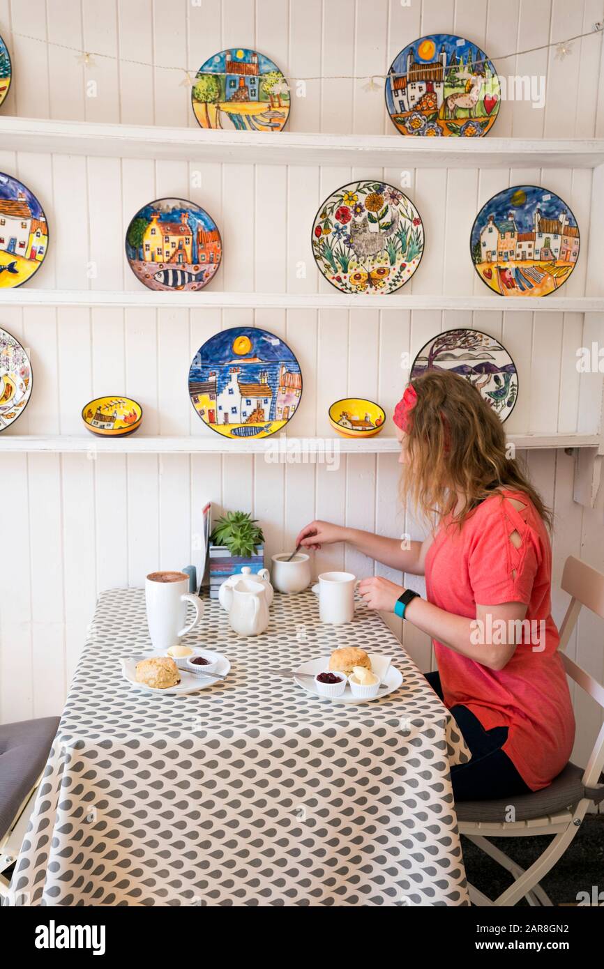 Blonder Teenager hat Tee und Scones in einem kleinen Café in St. Monans Dorf, Fife Coastal Path, Schottland, Großbritannien, Europa Stockfoto
