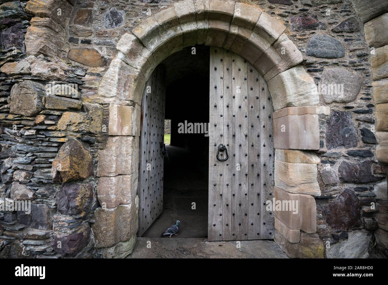 Die Tordurchfahrt hat eine massive, abgenutzte Holztür, die von Steinziegeln umgeben ist. Dunstaffnage Castle aus dem 13. Jahrhundert ist eine der ältesten Burgen Stockfoto