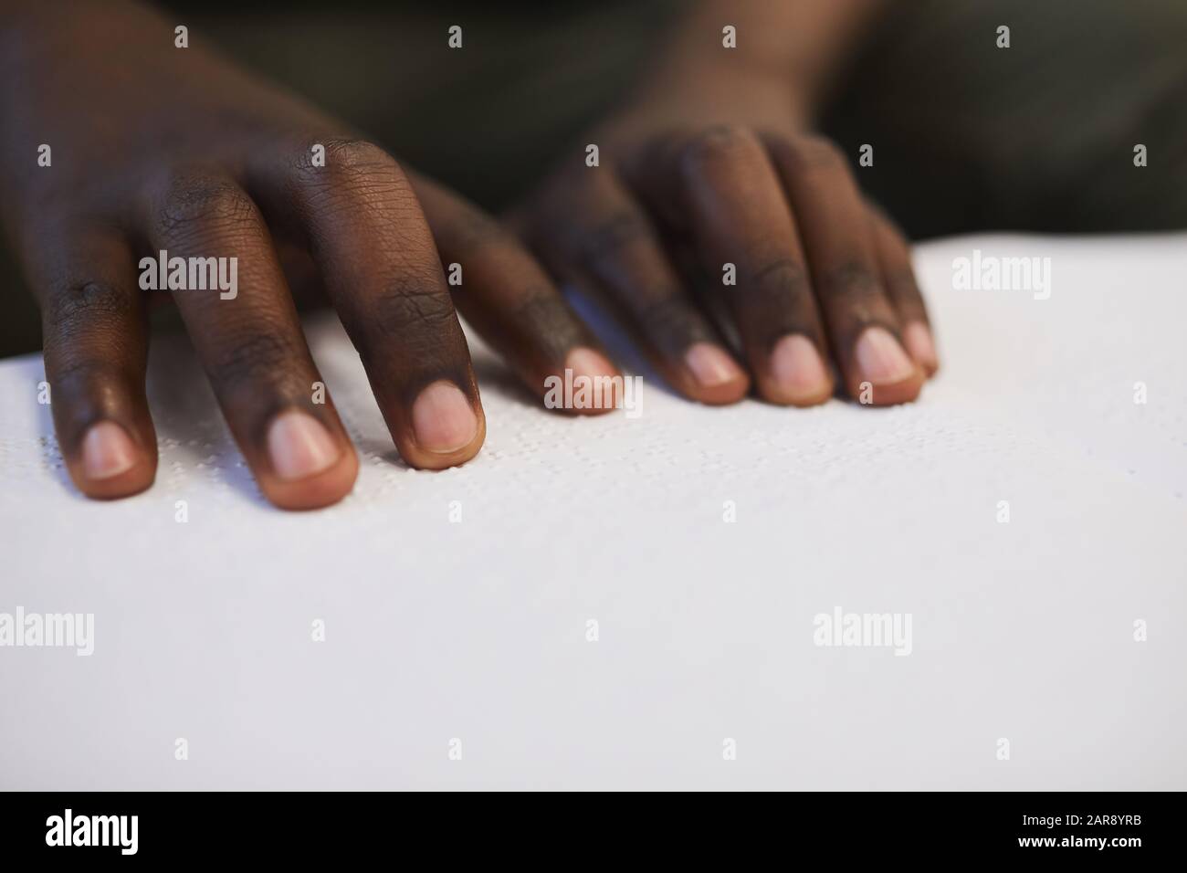 Nahaufnahme des nicht erkennbaren blinden Afrikaners, der Braillebuch liest, während er in der Schule studiert, kopiere Raum Stockfoto