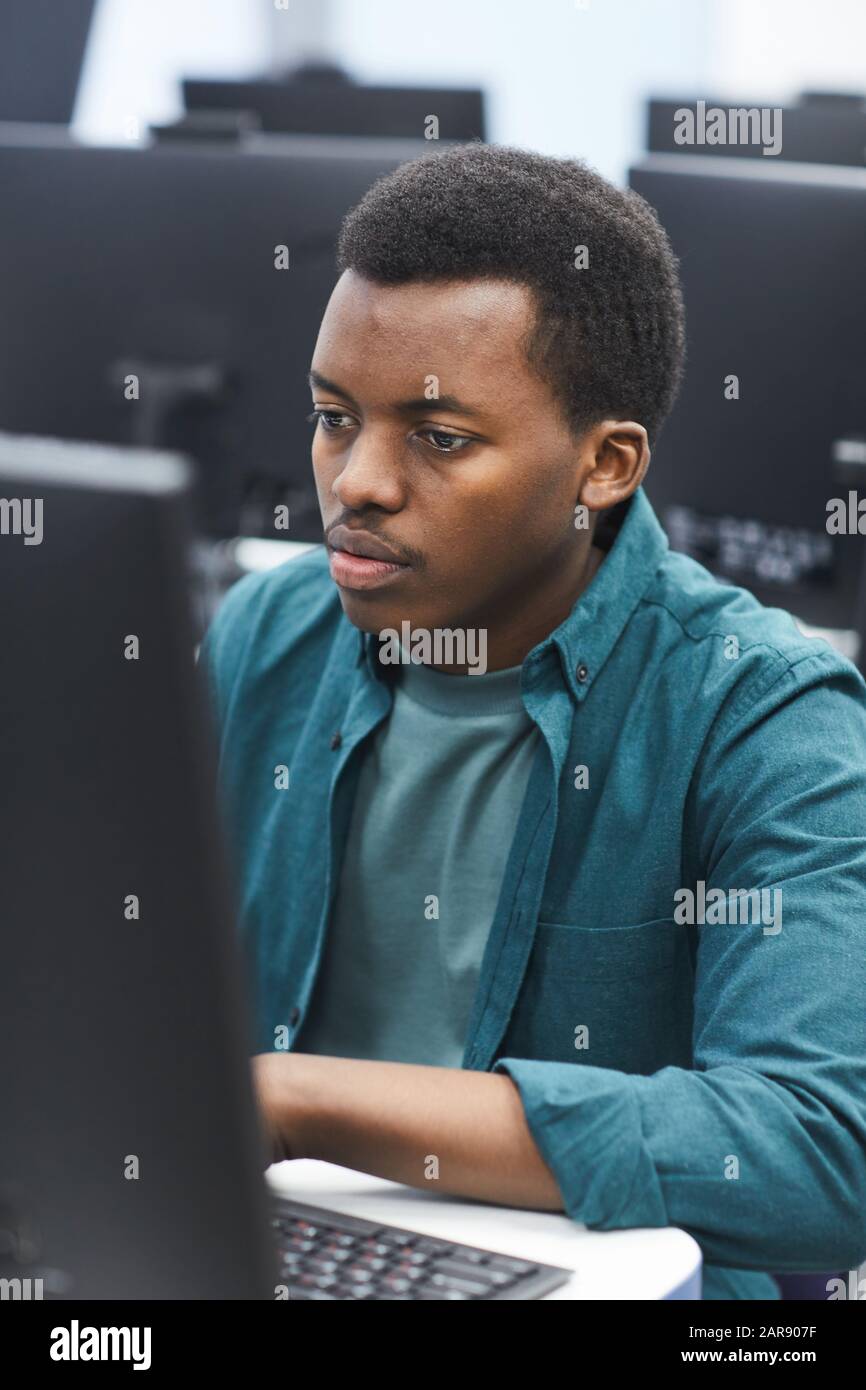 Hochwinkeliges Porträt eines afroamerikanischen Mannes, der Computer in der Klasse der College-Bibliothek verwendet, Kopierraum Stockfoto