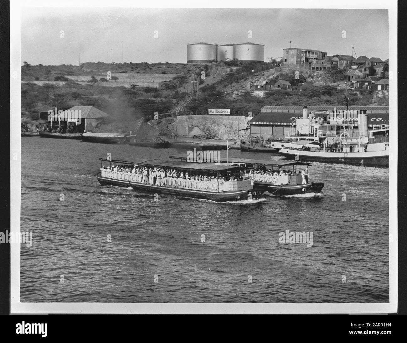 Wi [West Indies]/Anefo London Serie Zwei Fähren von C.P.I.M. (Curaçao Petroleum Industrie Mijn.) für den Transport der Mitarbeiter von und zu ihrem Arbeitsort im Hafen von Willemstad. Teilweise sichtbar das Dock der Curaçao Trade Me Rechts. Anmerkung: Repronegativdatum: {1940-1945} Ort: Curaçao, Willemstad Schlüsselwörter: Häfen, Hauptstädte, Weltkrieg, Fähren Stockfoto