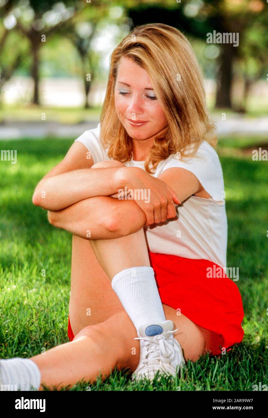 Eine junge Erwachsene Frau macht Dehnübungen, bevor sie in einem Long Beach, CA. Stadtpark joggt. MODELLFREIGABE Stockfoto