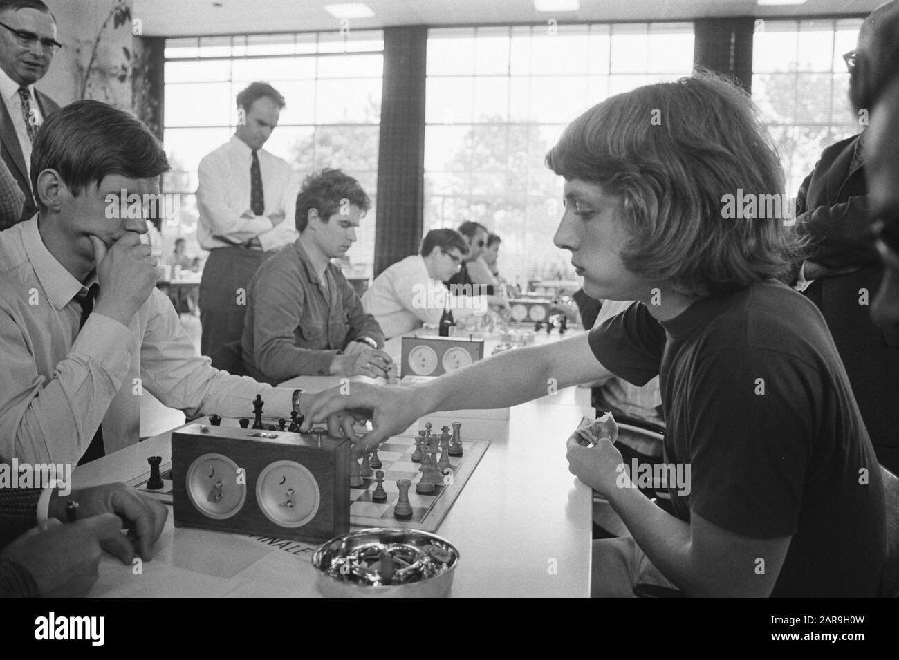 Niederländischer Meisterschafts-Speed-Schach bei Weesp-Wettkampfstatue, Timman (r) gegen Kuijpers. Timman isst gleichzeitig ein Sandwich. Anmerkung: Marginals Negativstreifen: 13: Jan Timman, Porträt; 15: Kuijpers (l) versus Timman Datum: 5. Juni 1971 Ort: Noord-Holland, Weesp Schlüsselwörter: Schach, Sport, Wettbewerbe persönlicher Name: Kuijpers, Französisch, Timman, Jan Stockfoto